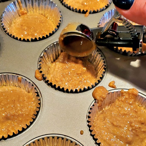 Peanut butter cups being scooped into muffin tin
