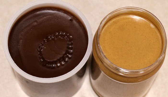 Open container of chocolate frosting and  creamy peanut butter. 