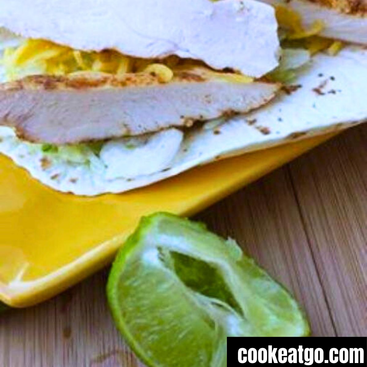 LIme chicken tacos served on a yellow plate with a lime wedge next to it 