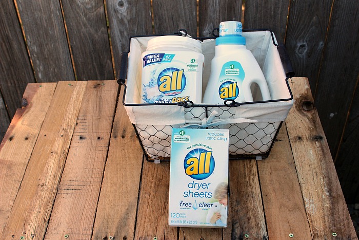 Top of diy pallet shelf with basket of detergent, softner, and dryer sheets