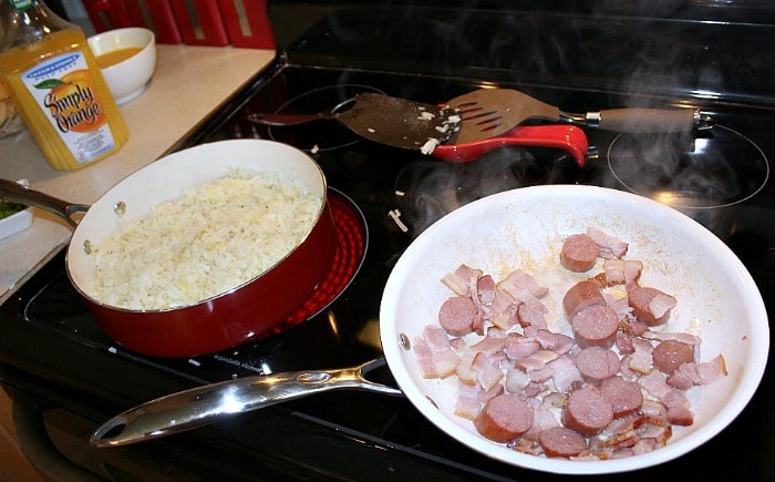 Frying pan with bacon and sausage rope, and second frying pan with hashbrowns on a stove top