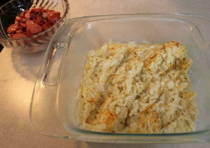 Hashbrowns in casserole pan with cooked sausage in a dish