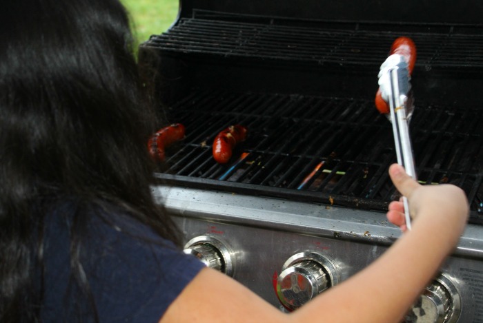 Isabella Flipping Bratwurst on the grill