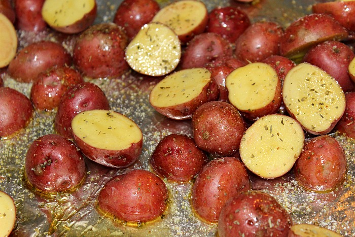 Sliced Baby Red Potatoes covered in olive oil and Italian seasoning on cookie sheet covered in tinfoil