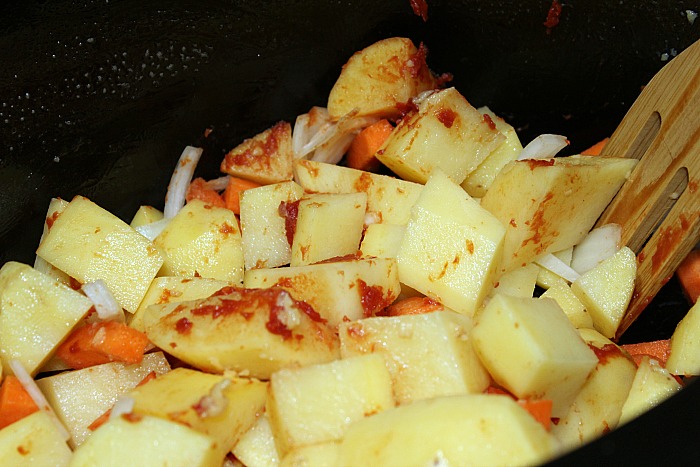 potatoes, carrots, and onion in crockpot mixed with tomato paste