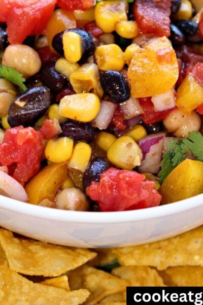 Cowboy Caviar bean Salad Served in a white bowl with with a layer or tortilla chips around it