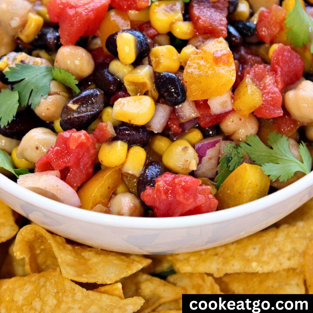 Cowboy Caviar bean Salad Served in a white bowl with with a layer or tortilla chips around it