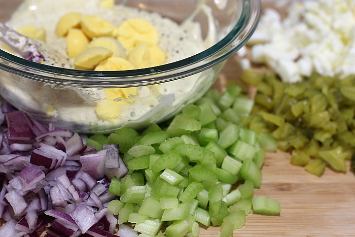 Diced Onions, Celery, Pickles, and Egg whites next to a bowl of Mayo, seasoning, and egg yolks