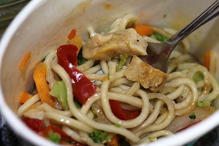 Cooked chicken chow mein in container stirred with fork