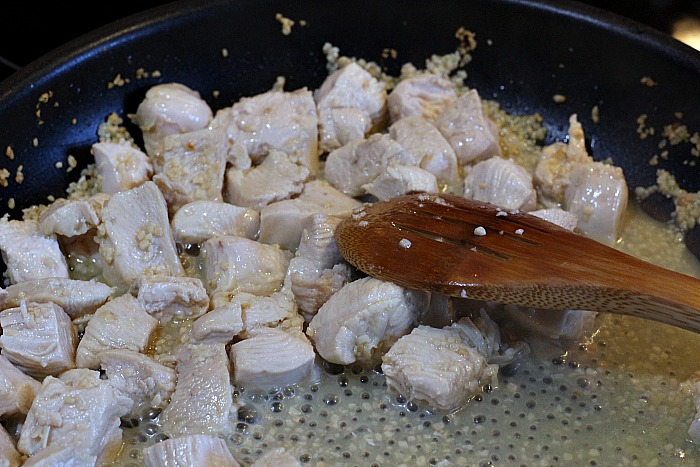 Chicken sautéing in frying pan in garlic and olive oil