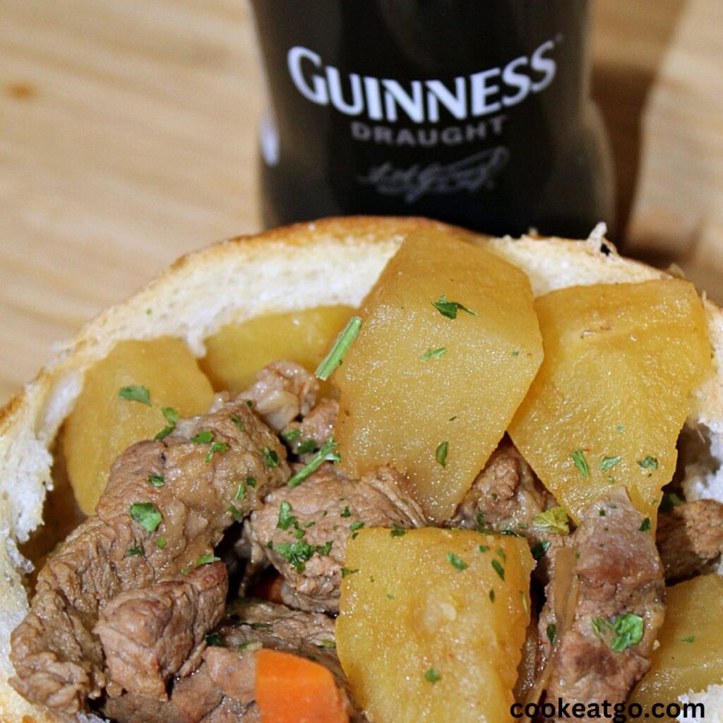 Bread bowl with Guinness Beef Stew in it with a bottle of Guinness 