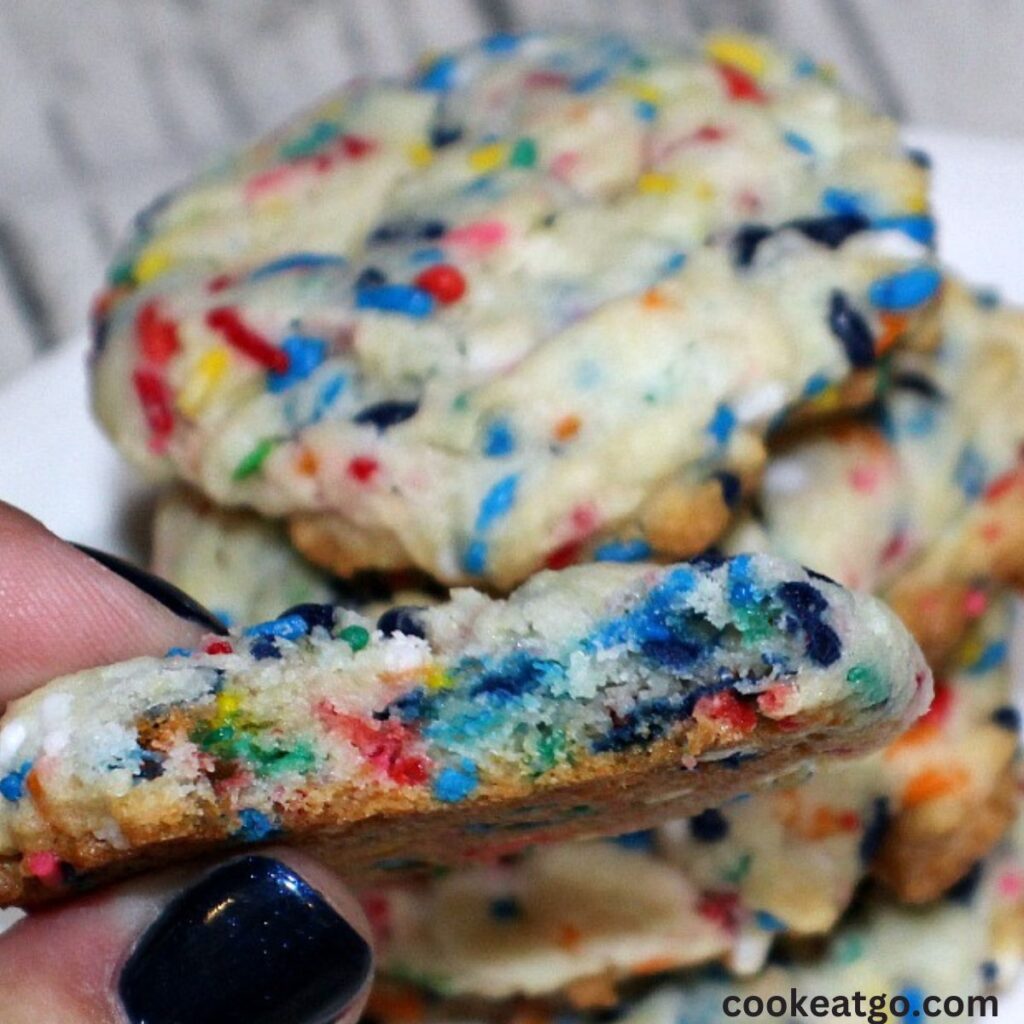 Funfetti Cookies with a bite out with stack of cookies behind it 