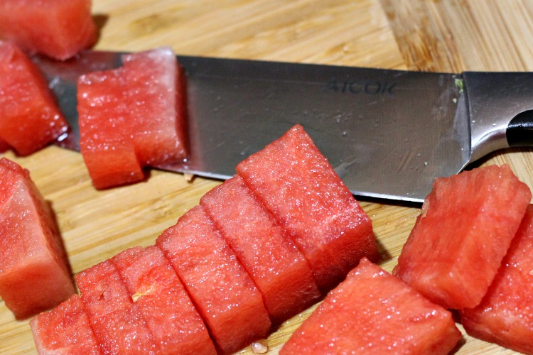 Watermelon cut with knife next to it 