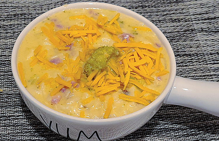 Crockpot Creamy Cheese Broccoli Potato Soup served and topped with cheese in a bowl.  