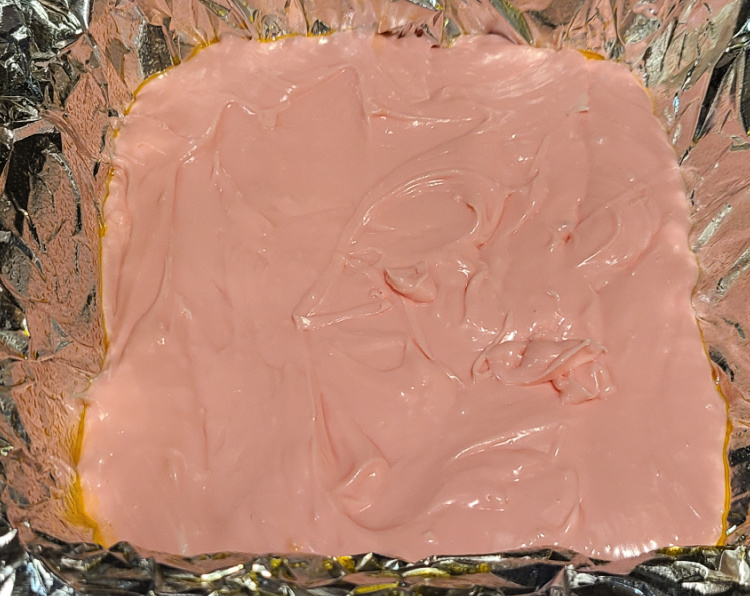 Strawberry 2 ingredient fudge in pan on tinfoil before setting in fridge