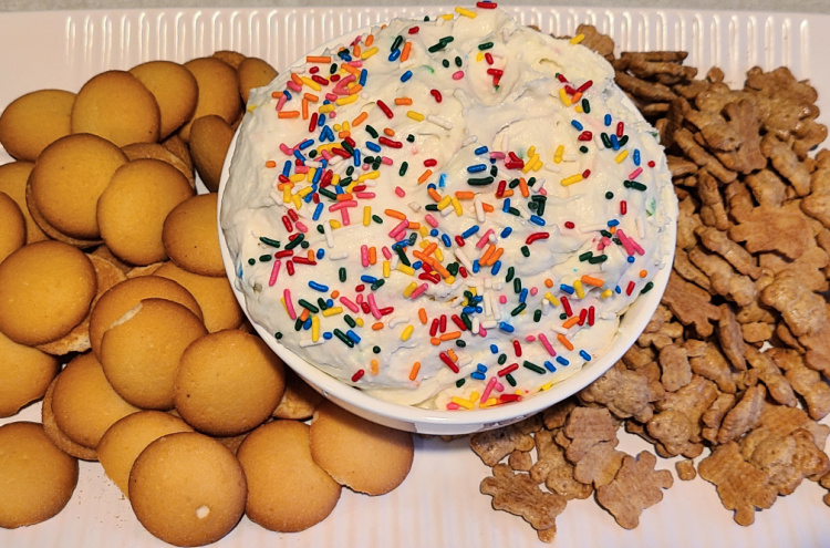 Funfetti Cake Dip in a bowl with vanilla wafers and teddy grahams around it on a platter. 