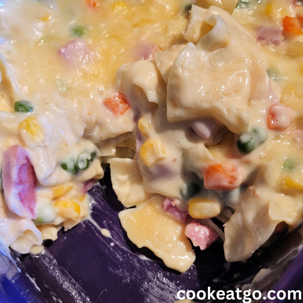 Cheesy Ham Noodle Casserole in casserole dish with piece served