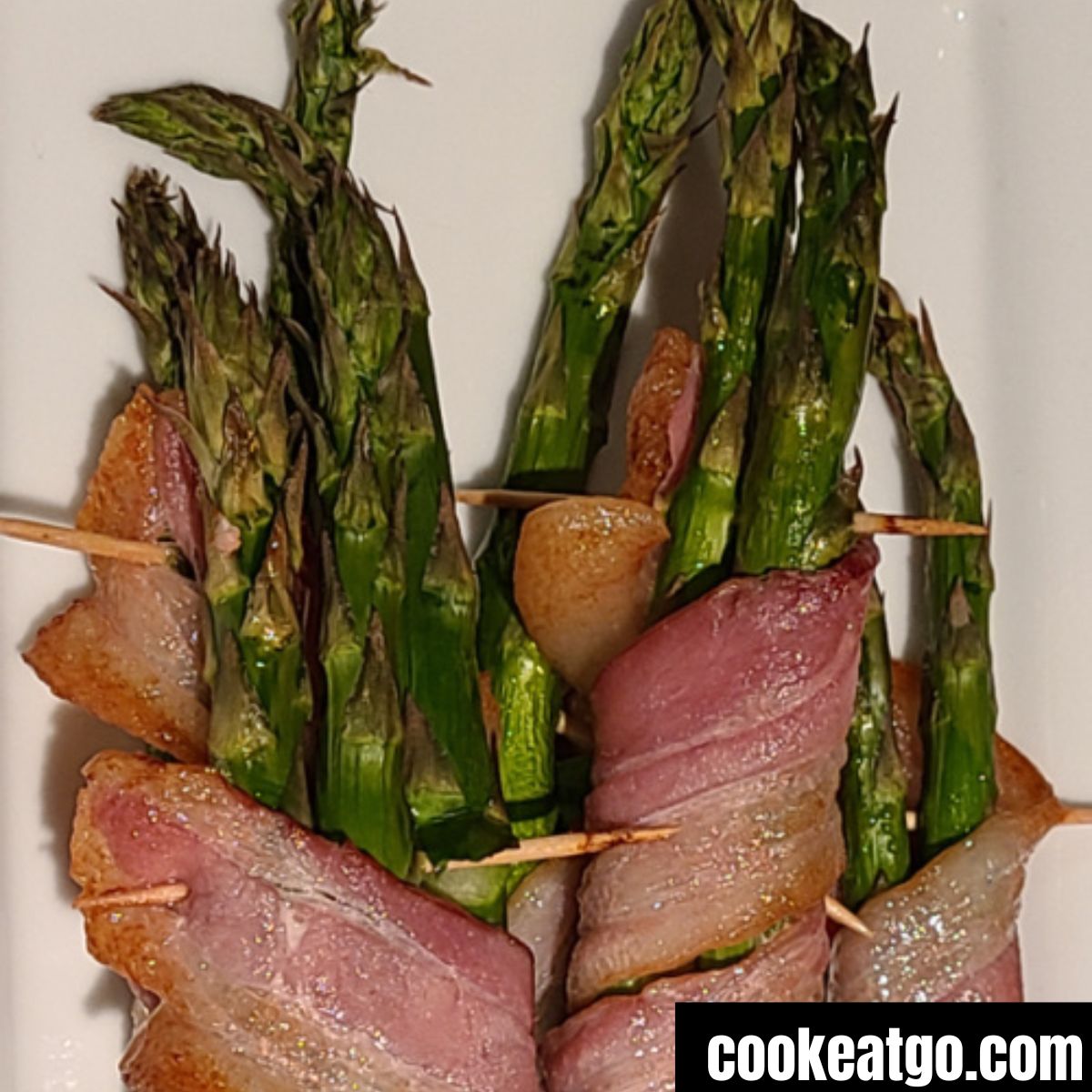 Air Fryer Asparagus wrapped in bacon on a white plate