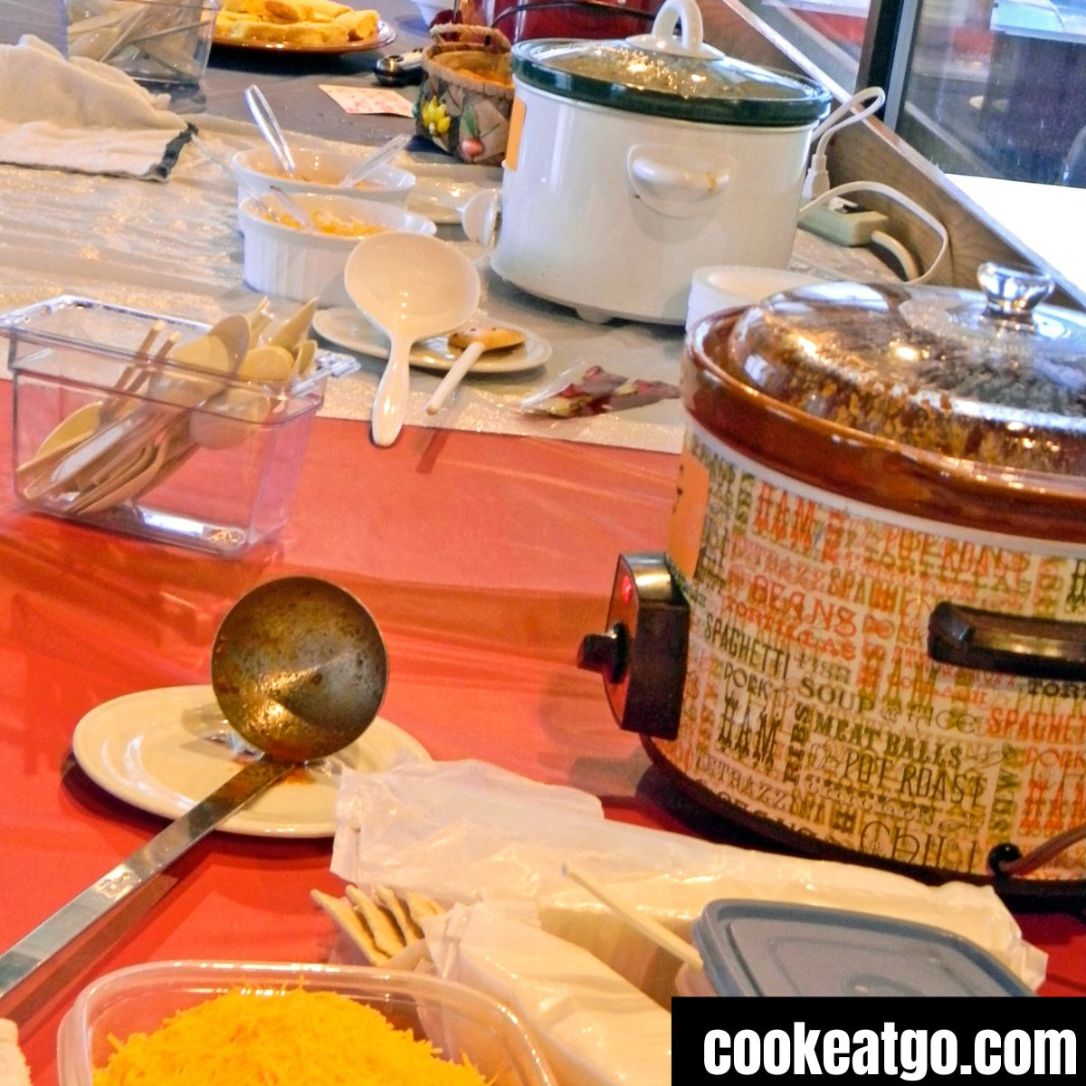 Crockpots on a table with serving utensils and other assorted food