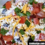 Bacon ranch pasta salad served in a dish topped with bacon, tomatoes, and shredded cheese.