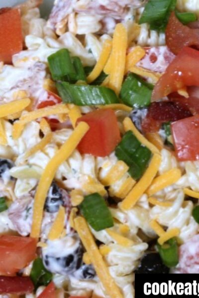 Bacon ranch pasta salad served in a dish topped with bacon, tomatoes, and shredded cheese.