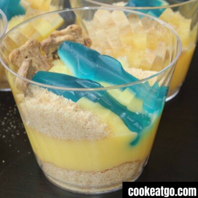 Dirt cups with graham crackers vanilla pudding and shark gummies in them to make a shark sand cup