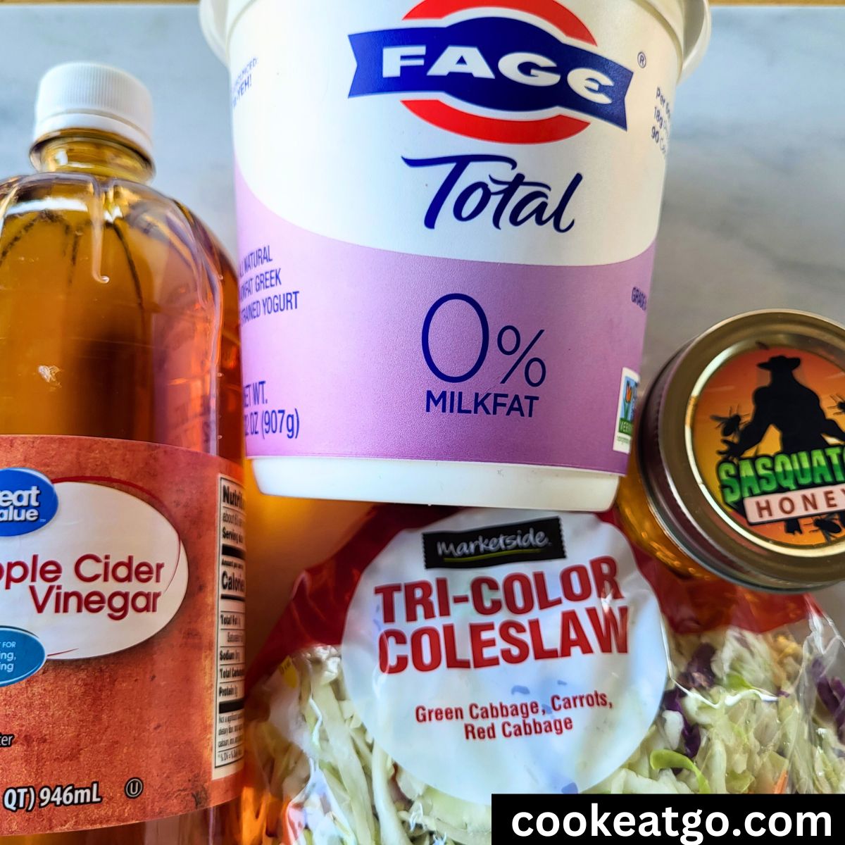 Apple cider vinegar, greek yogurt, honey in a jar, and a bag of cole slaw mix