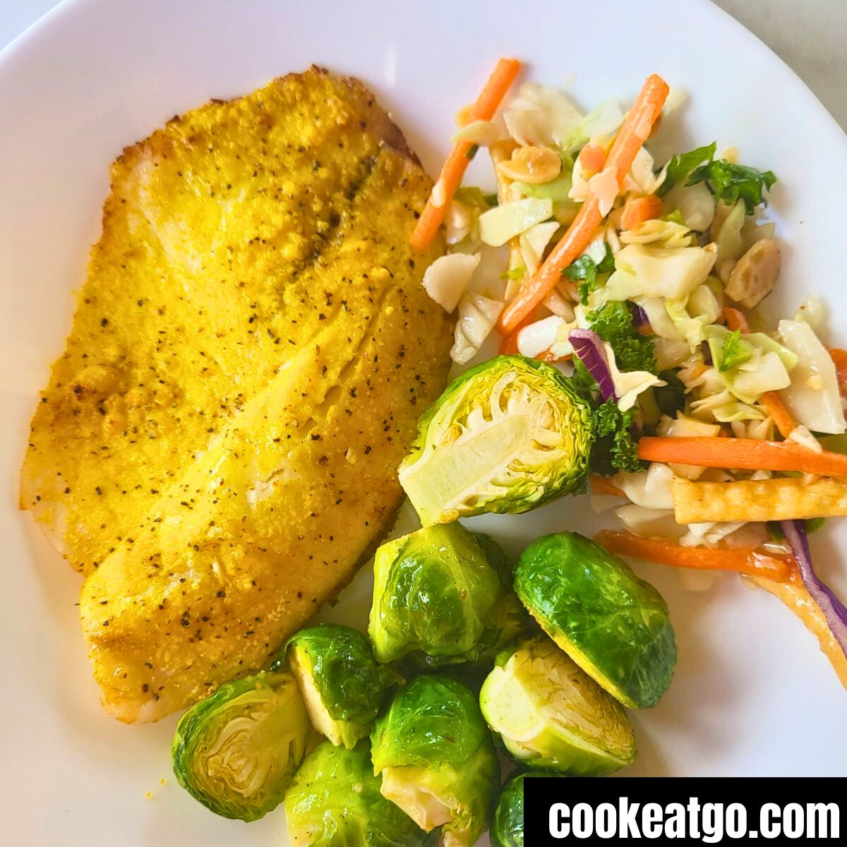 Air Fryer Brussel Sprouts Served with Lemon Pepper Tilapia and asian salad on a white plate