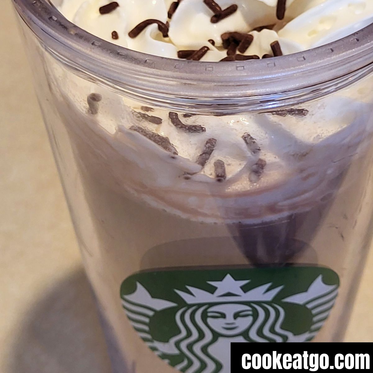 Starbucks venti clear cup with skinny mocha topped with whipped topping and chocolate sprinkle