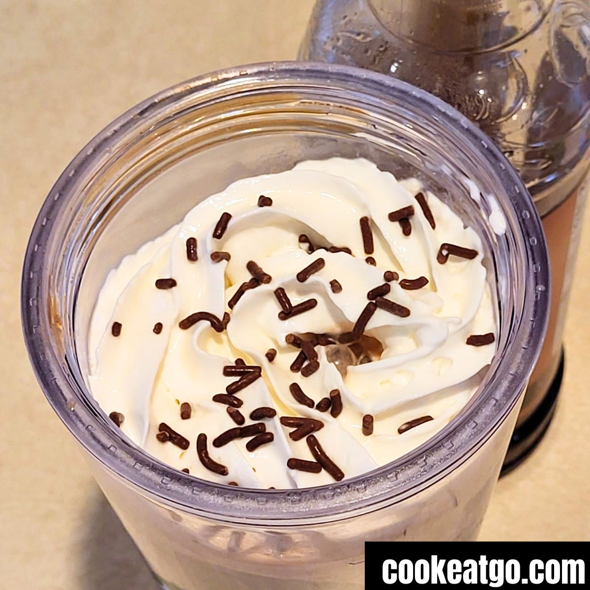 Skinny Mocha topped with whipped topping and sprinkles next to skinny mocha syrup