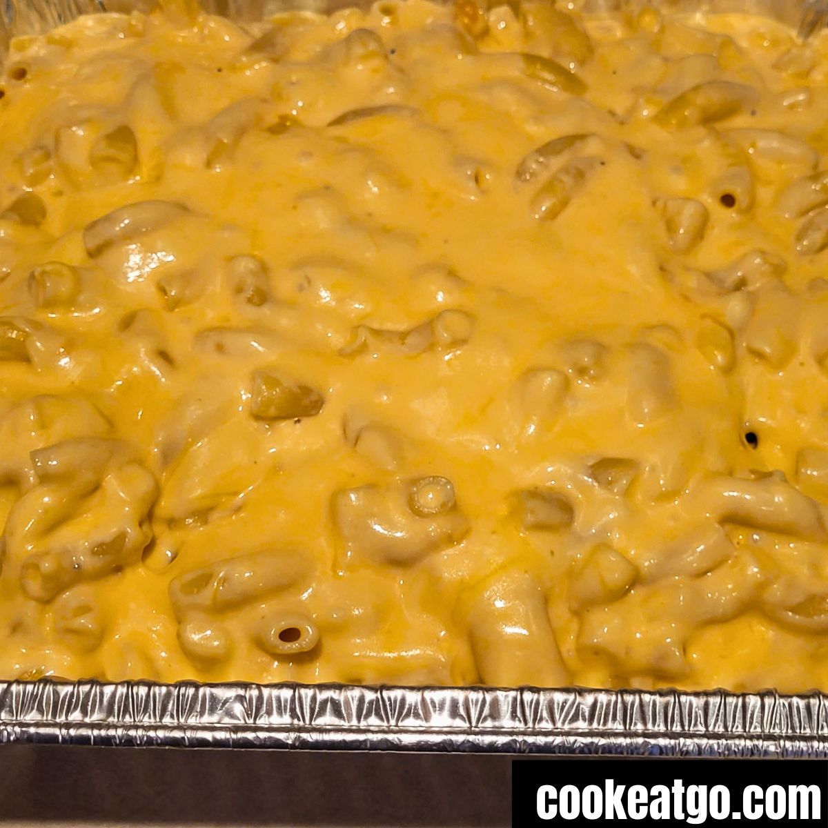 Melted Cheese over macaroni noodles in tin foil pan