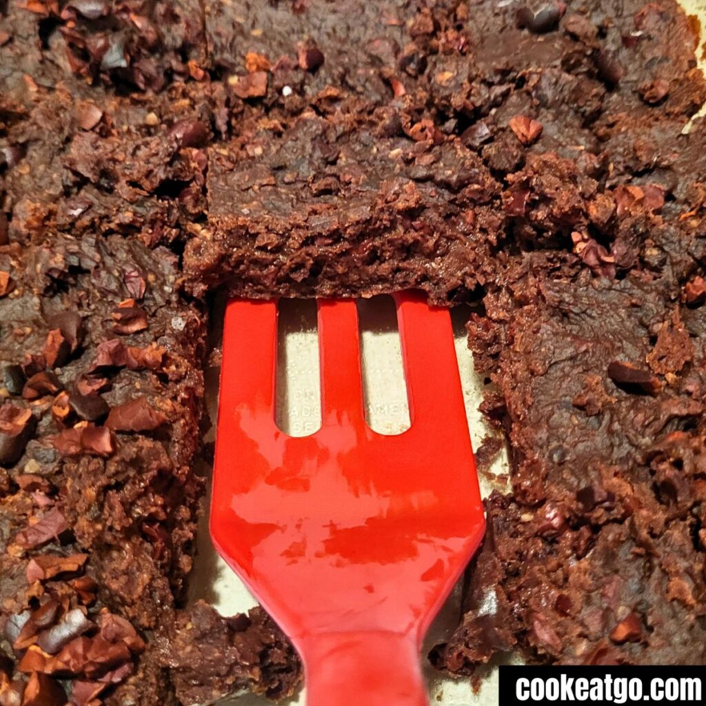 black bean brownies baked in pan with some missing and a red spatual in it