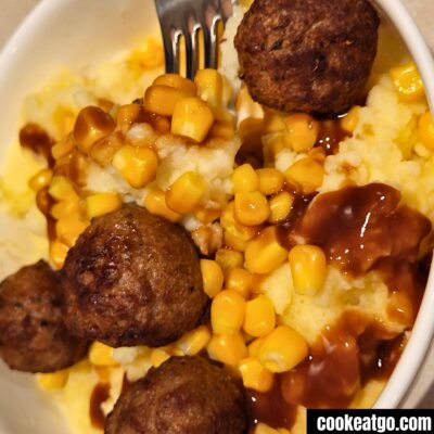 Meatball mashed potato bowl served in a white bowl with a fork