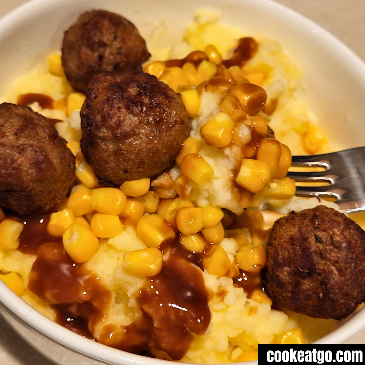 Fork scooping out meatball potato bowl