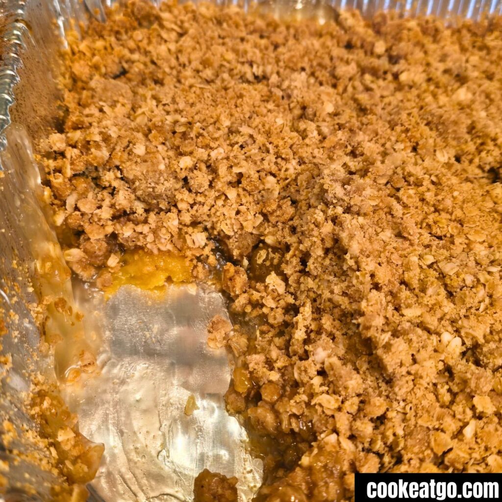 Peach Crisp in foil pan with piece missing