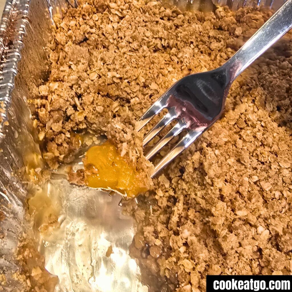 Peach Crisp in tin foil pan with fork