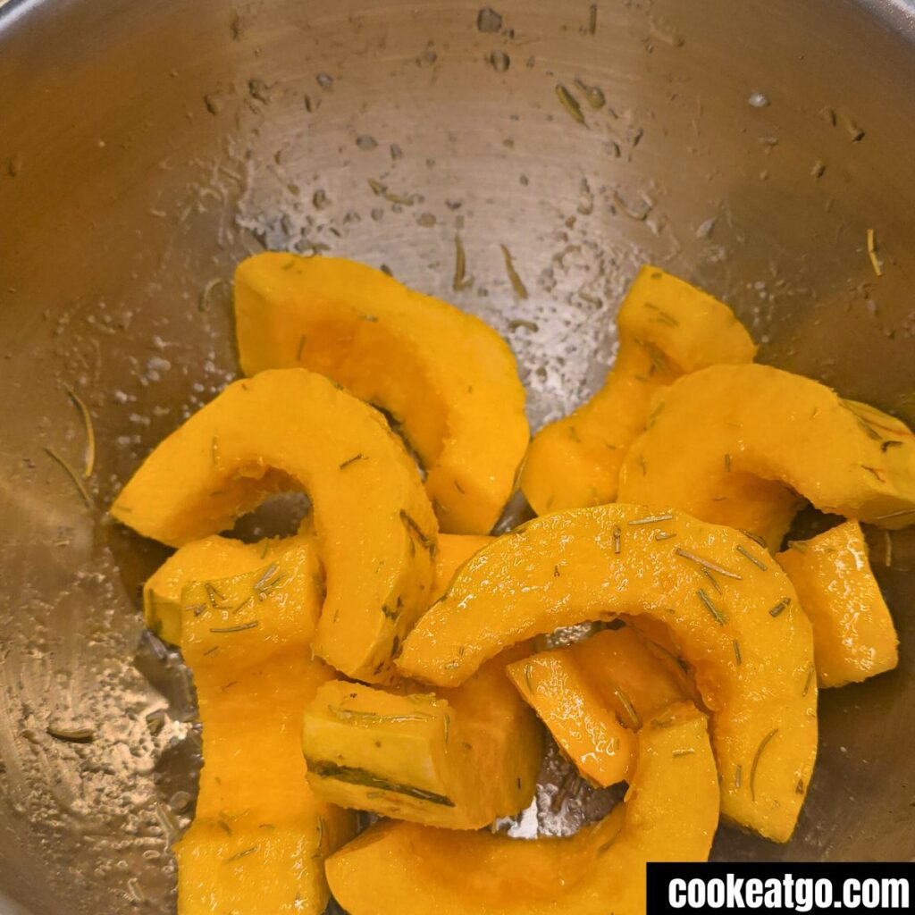 Delicata Squash seasoned with rosemary in mixing bowl