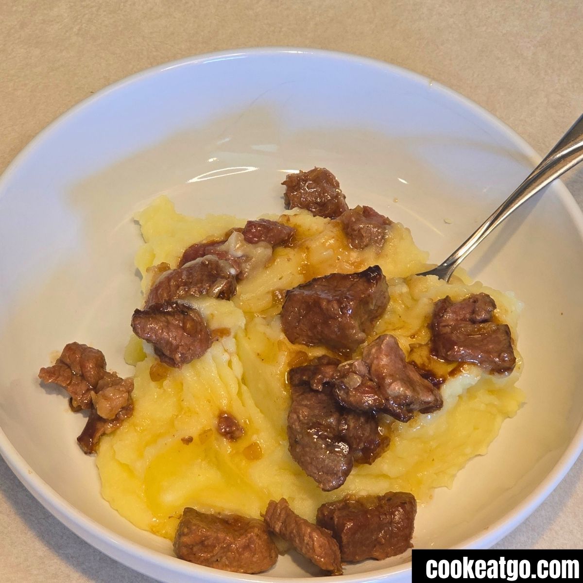 Slow Cooker Beef Tips served in Mashed Potatoes
