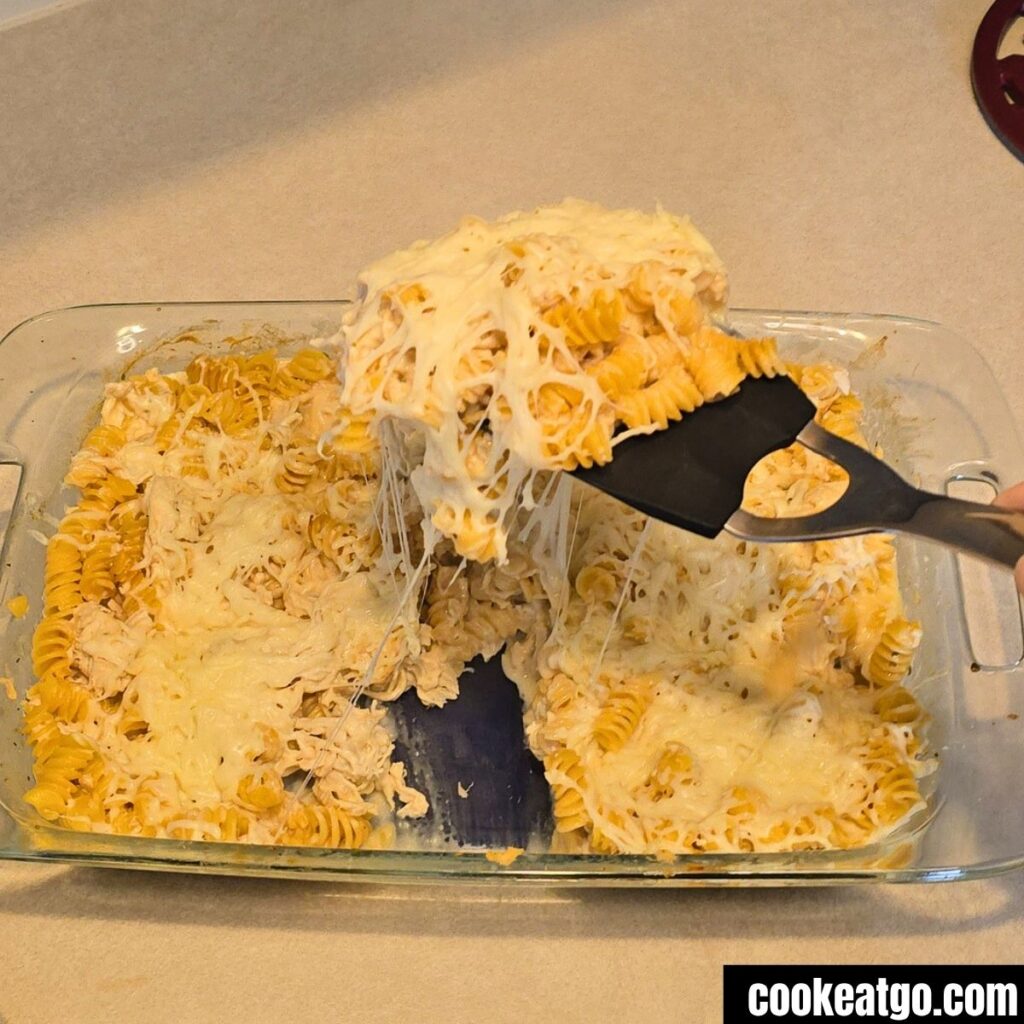 Spatula Pulling a serving of creamy italian Chicken Bake With A Cheese pull